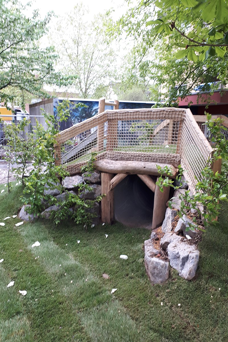 Neu gebautes Spielgerät aus Holz und Naturstein auf einem Kindergarten-Spielplatz
