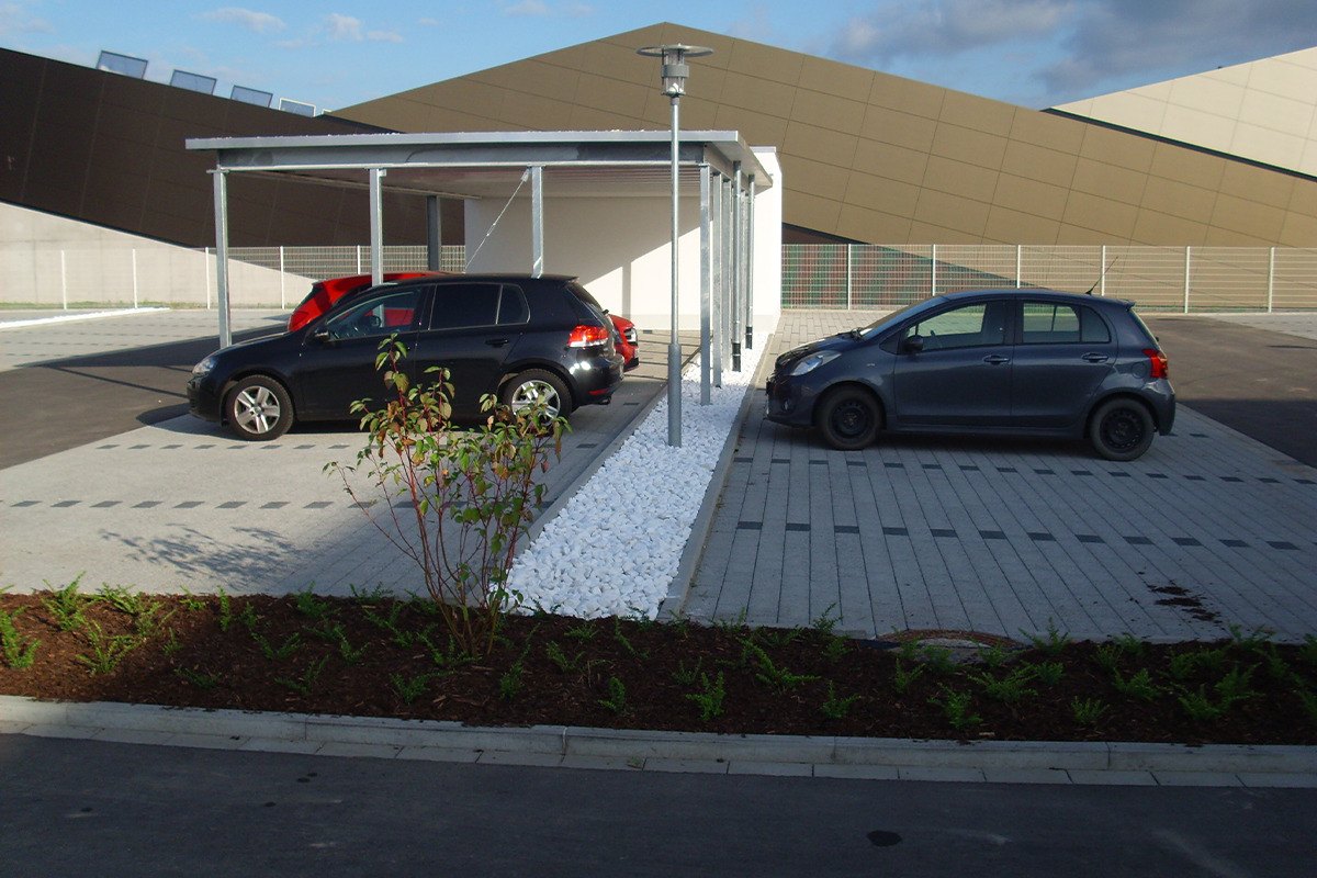 Gepflasterte Stellplätze mit Carport und neuer Bepflanzung an einer Gewerbeanlage