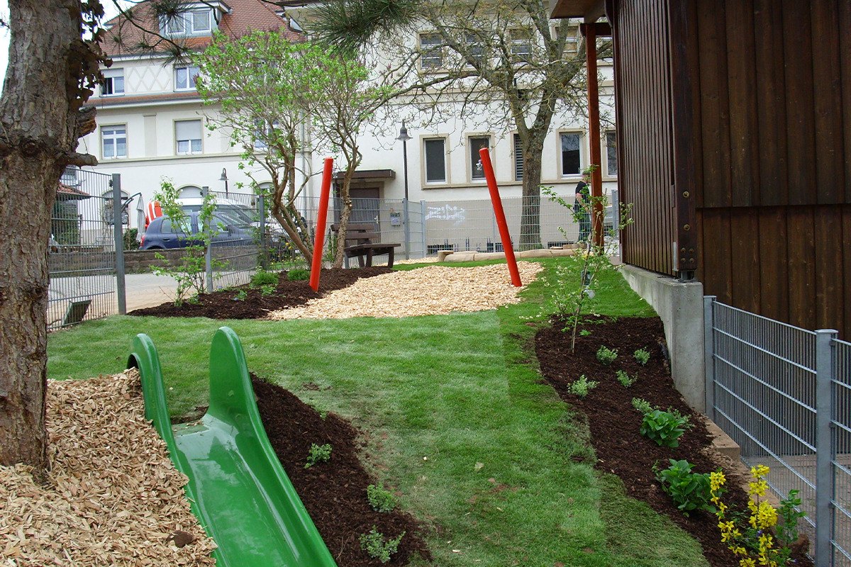 Neu angelegter Kindergarten-Spielplatz mit Rutsche im Rasenhügel