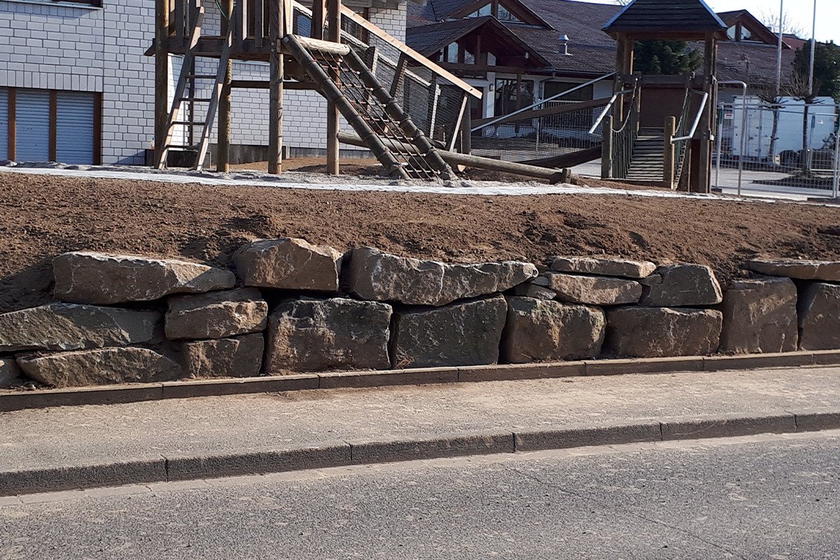 Natursteinmauer aus großen Sandsteinblöcken an einer Straße